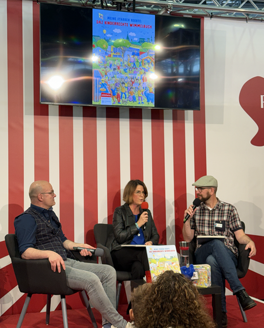 https://www.kinderschutzbund-mainz.de/public/assets/wimmelbuch_buchmesse_podium-2.png